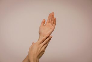 Close-up of hands gently caressing each other, symbolizing self-care and softness.