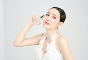 Serene model holding skincare product in modern beauty photoshoot.