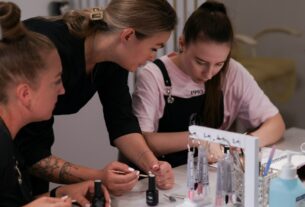 a group of women sitting around a table working on nail polish